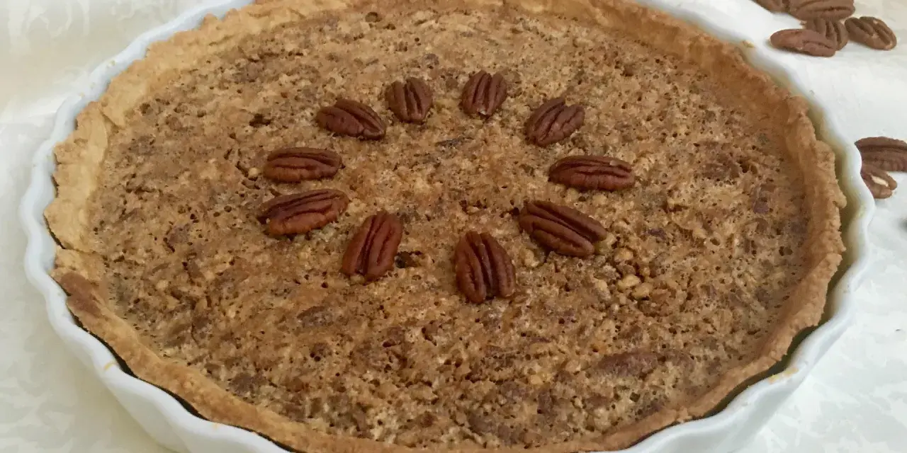 Torta di noci croccante e dorata, decorata con noci intere disposte a cerchio. Un delizioso pandi noci pronto da gustare.