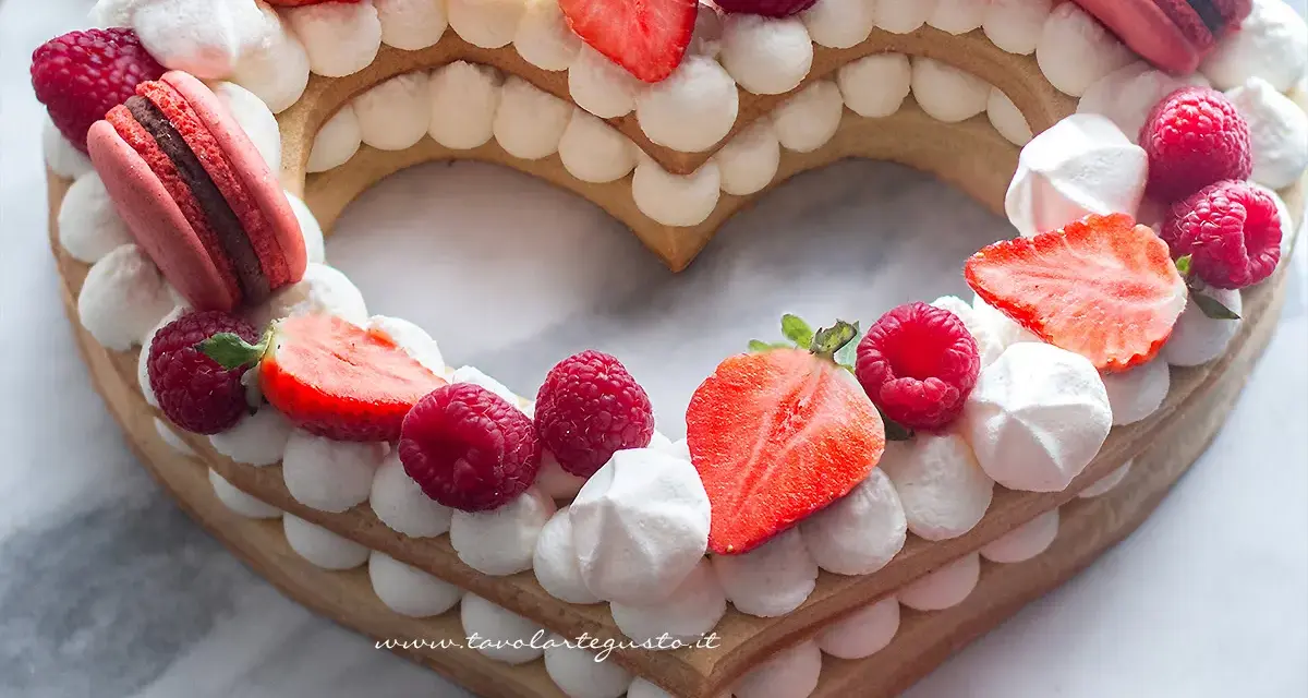 Cream tart numero 1 a forma di cuore, decorata con panna, fragole, lamponi e macarons.