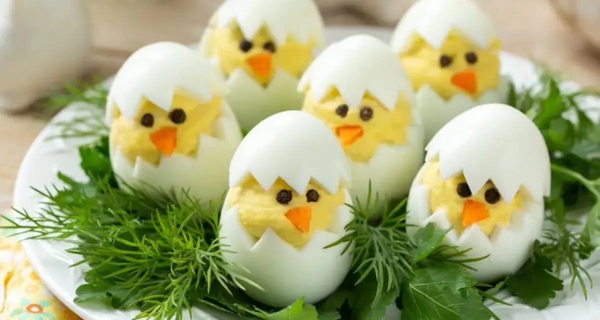 Uova sode ripiene a forma di pulcino, un'idea divertente per le jajka faszerowane pasquali, adagiate su un letto di erbe aromatiche.