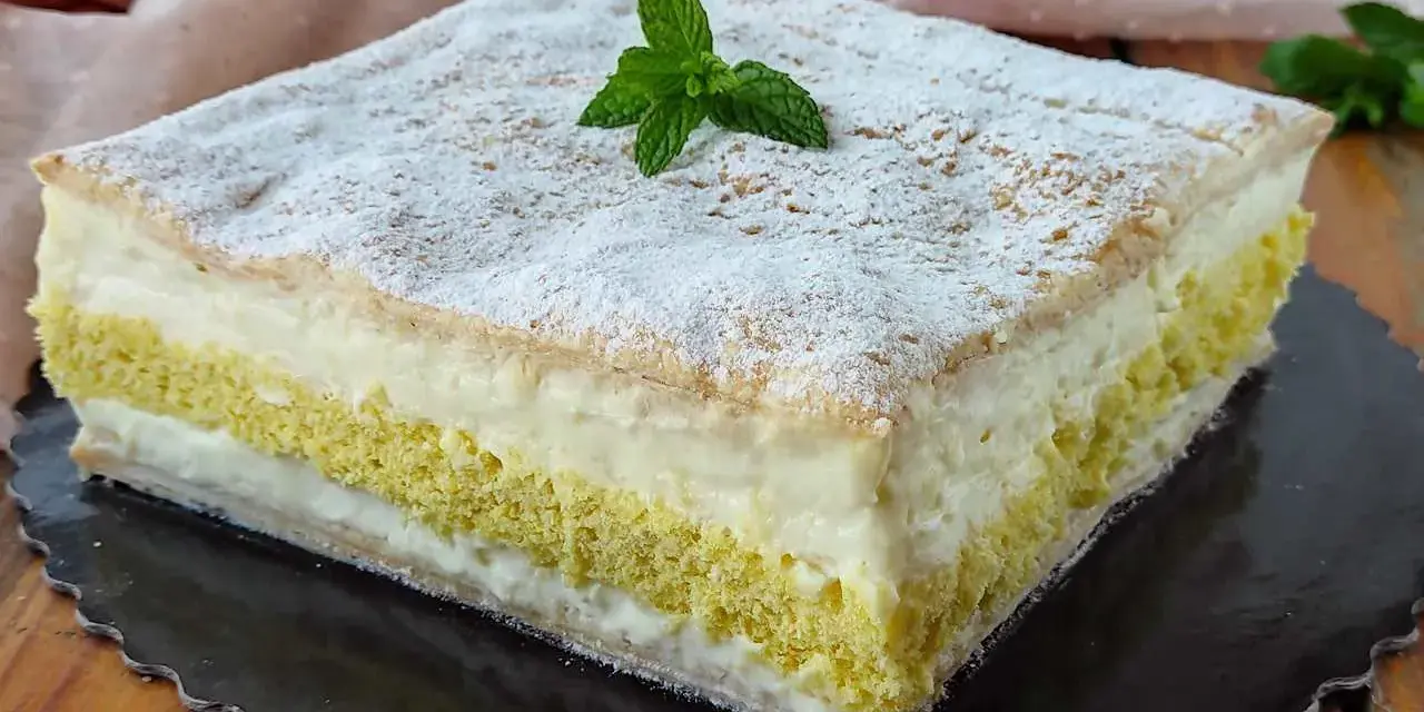 Una deliziosa torta di compleanno con pasta sfoglia e pan di spagna, farcita con crema e decorata con zucchero a velo e menta.