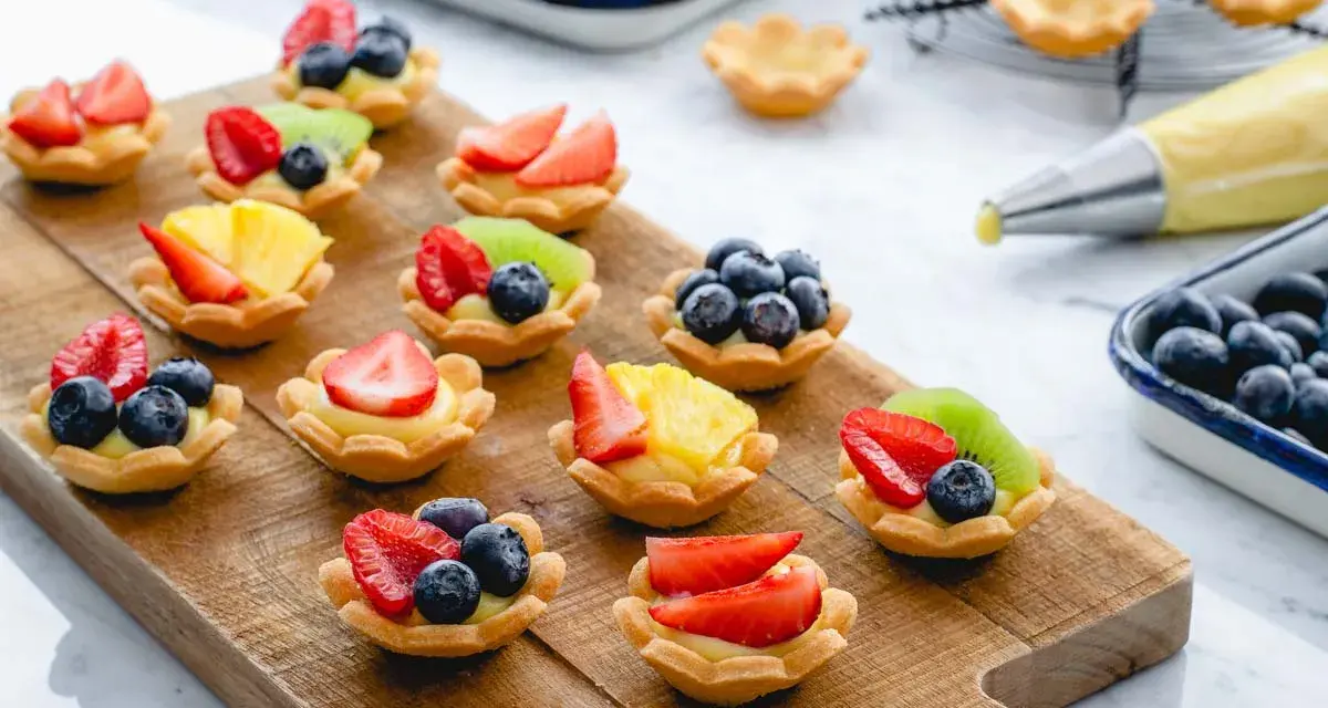 Deliziosi cestini di frutta ricetta, preparati con fragole, mirtilli, kiwi e ananas su una base di crema.