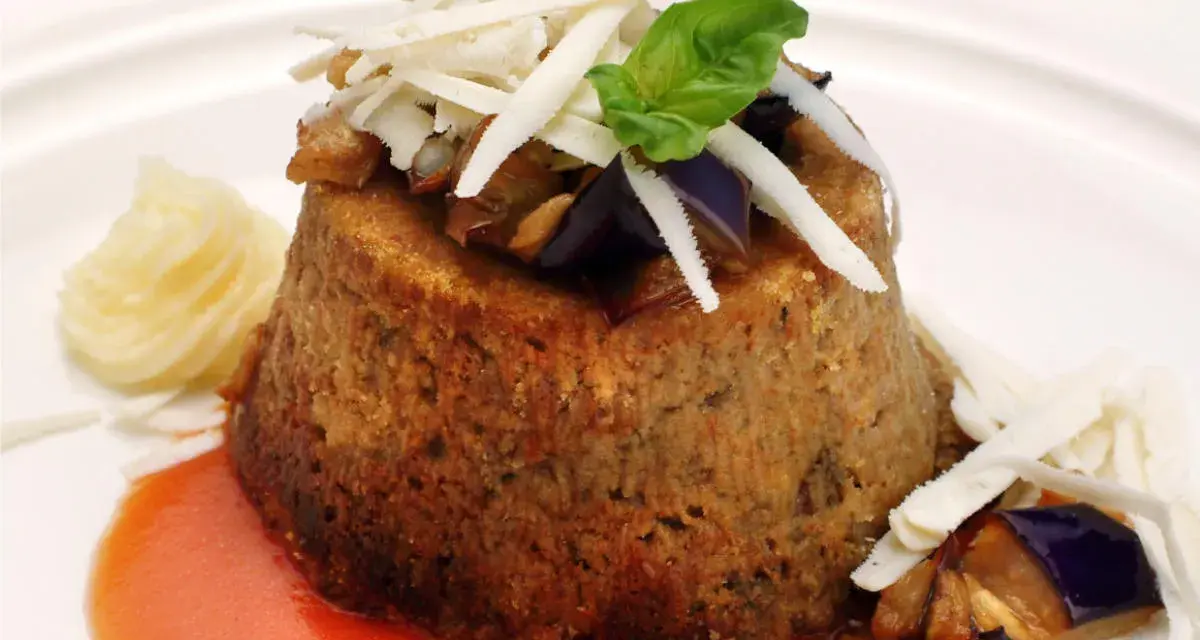 Sformato di melanzane leggero, guarnito con scaglie di formaggio, basilico e servito con salsa rossa e purè.