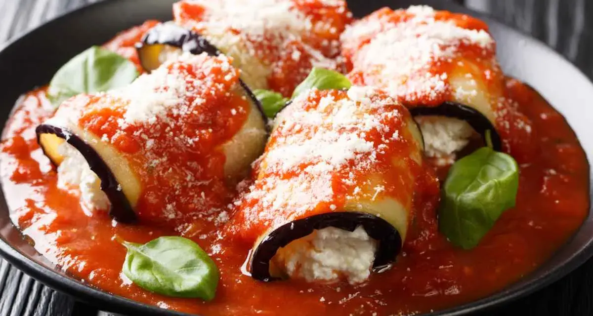Involtini di melanzane vegetariani ripieni di ricotta, coperti da sugo di pomodoro e parmigiano, guarniti con basilico fresco.