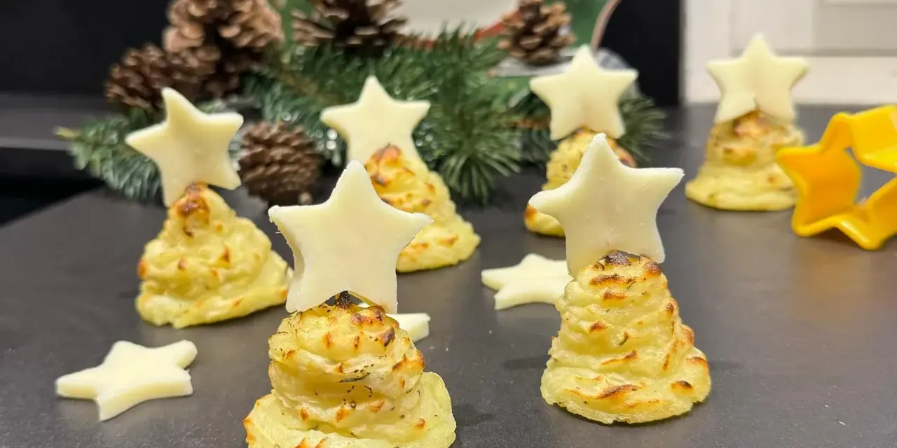 Alberelli di patate decorati con stelle di formaggio, su un piatto natalizio con pigne e rami di abete.