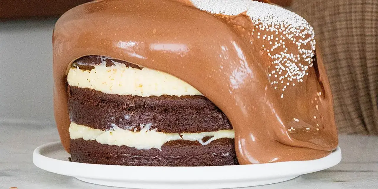 Torta al cioccolato a strati con glassa al cioccolato fusa che cola, decorata con perline bianche. Un vero tsunami di dolcezza!