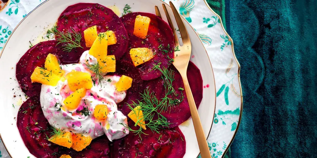Delizioso carpaccio di barbabietola con crema, arancia e aneto su un piatto decorato.