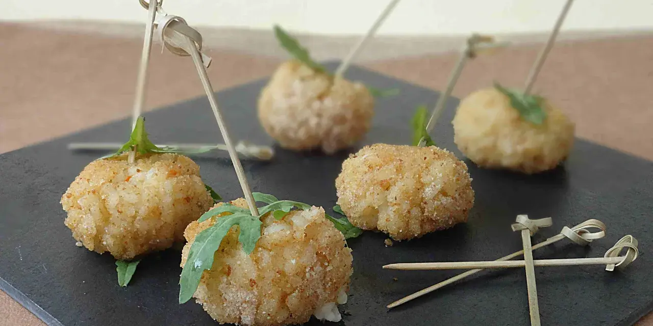 Deliziose polpette finger food con salsa, servite su una pietra scura, pronte per essere gustate.