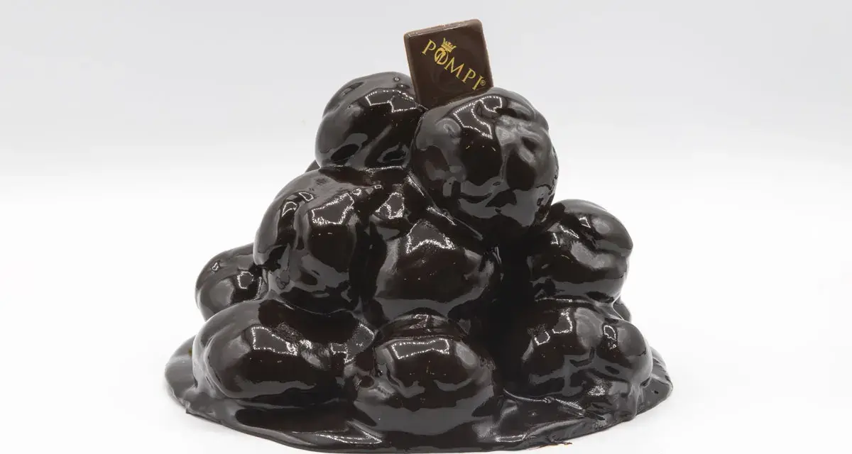 Torta profitterol compleanno, un tripudio di cioccolato lucido e goloso, coronata da un quadratino con logo.
