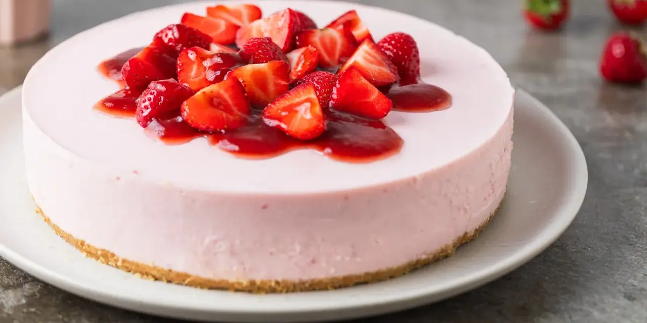 Cheesecake rosa con fragole fresche e salsa, un dolce delizioso, perfetto per ogni occasione.