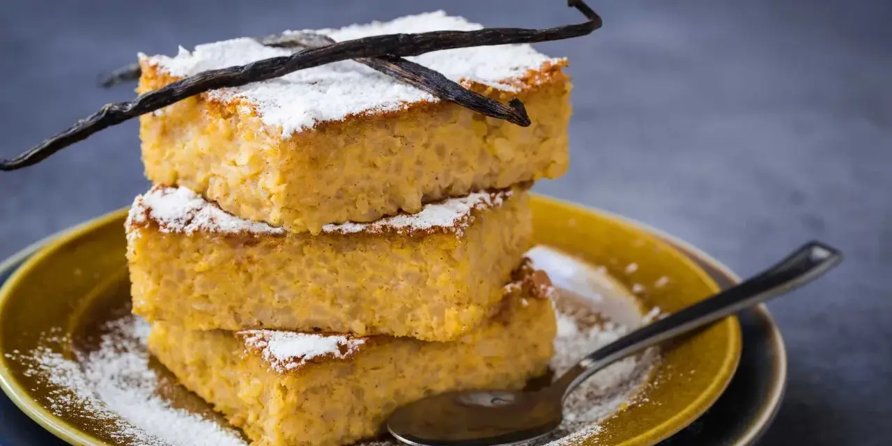 Tre fette impilate di torta di riso fiorentina, spolverate di zucchero a velo e decorate con baccelli di vaniglia.