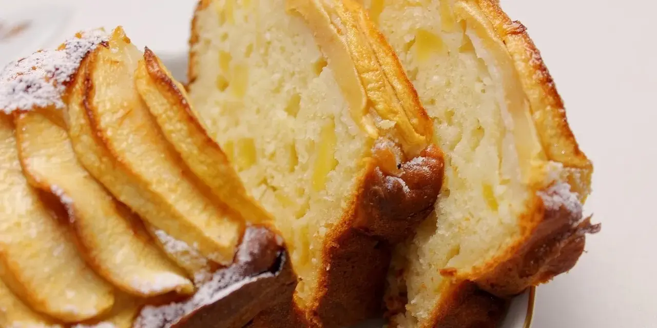 Fette di plumcake ricotta e mele, con mele a vista sulla superficie e spolverata di zucchero a velo.