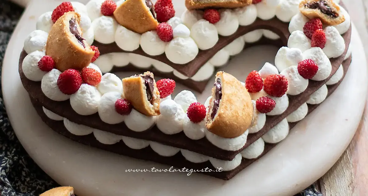 Cuore di pasta biscotto al cacao per cream tart, decorato con panna, fragoline e biscotti ripieni.