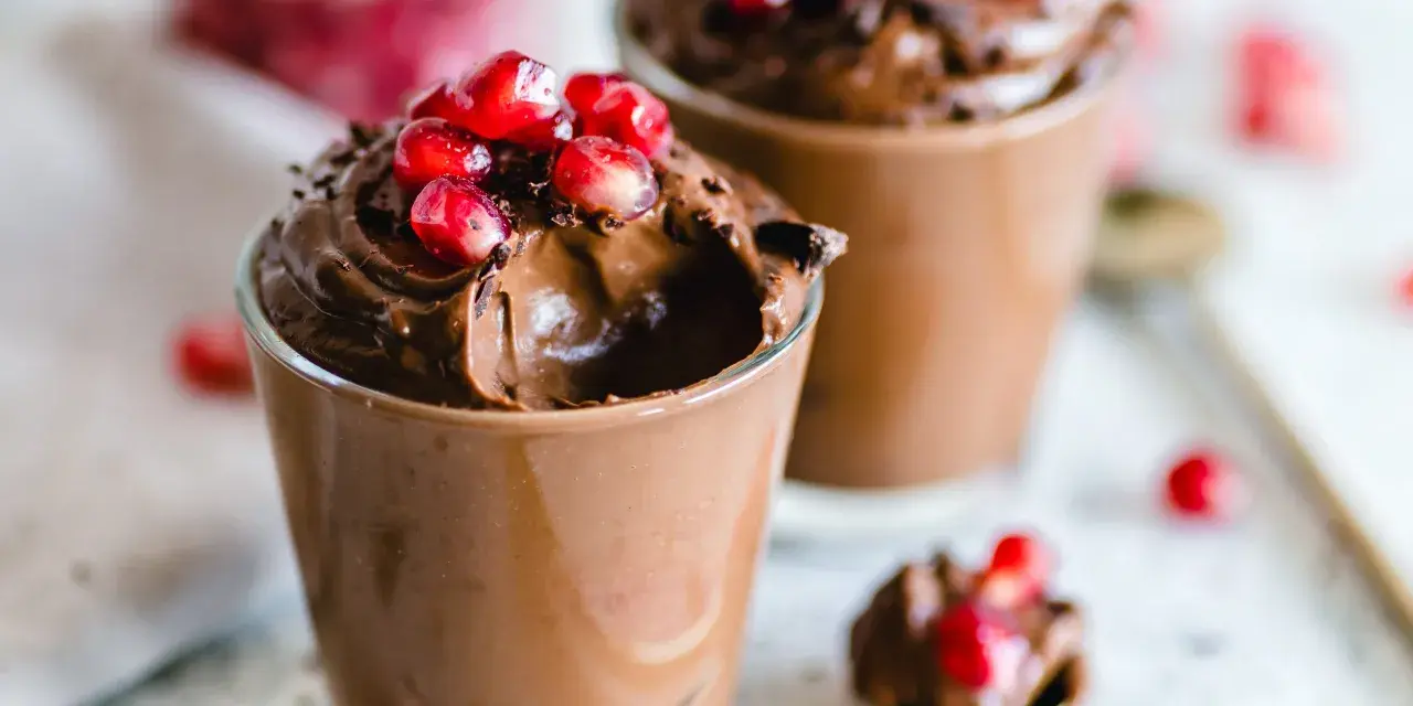 Mousse al cioccolato per profiterol, guarnita con chicchi di melagrana succosi. Un dessert goloso e invitante.