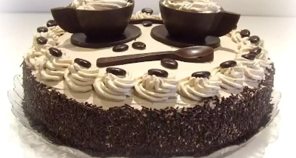Torta decorata con ciuffi di crema al caffè, chicchi di cioccolato e due tazzine di cioccolato riempite di crema. Un vero capolavoro per gli amanti del bagna al caffè.