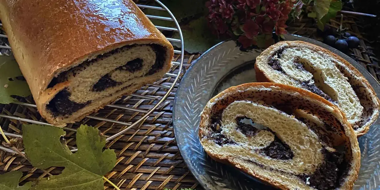 Makowiec japoński, un rotolo di pane dolce con ripieno di semi di papavero, tagliato a fette su un piatto decorato.