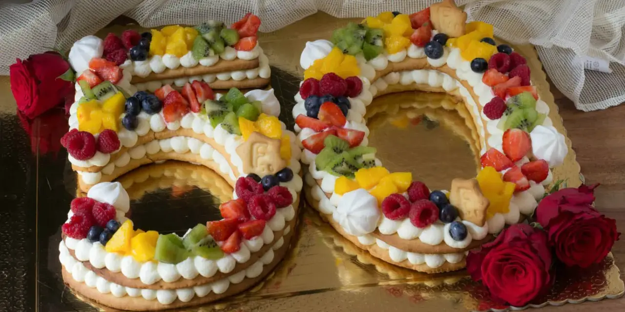Torta 50 anni con panna, frutta fresca e biscotti a forma di numero. Un dolce colorato e delizioso per festeggiare un traguardo importante.