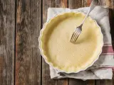 Pasta frolla salata con olio e parmigiano pronta per essere infornata. Una forchetta è appoggiata sulla base bucherellata.