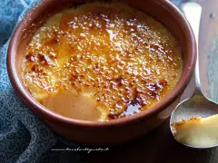 Un delizioso krem kataloński con crosta caramellata dorata, servito in una ciotola di terracotta.