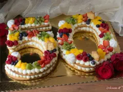 Torta 50 anni con panna, frutta fresca e biscotti a forma di numero. Un dolce colorato e delizioso per festeggiare un traguardo importante.