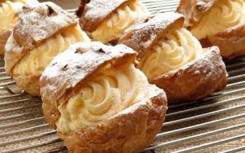 Bignè ripieni di crema pasticcera, spolverati di zucchero a velo. La farina per bignè W è perfetta per questa preparazione.