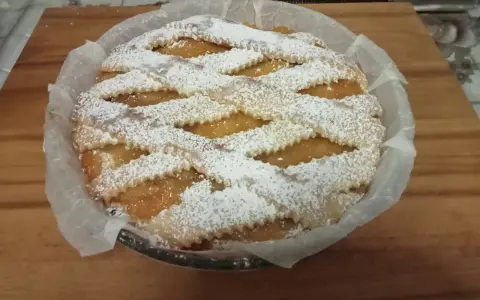 Una deliziosa crostata pasqualina salata, con un intreccio di pasta frolla cosparso di zucchero a velo, pronta per essere gustata.