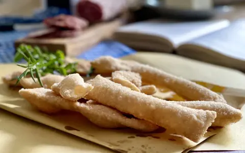 Sgabei fritti dorati e croccanti, profumati con rosmarino fresco, pronti per essere gustati con salumi e formaggio.