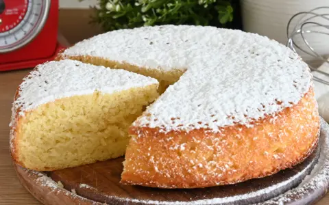 Delizioso ciasto jogurtowe, soffice e cosparso di zucchero a velo, pronto per essere gustato.