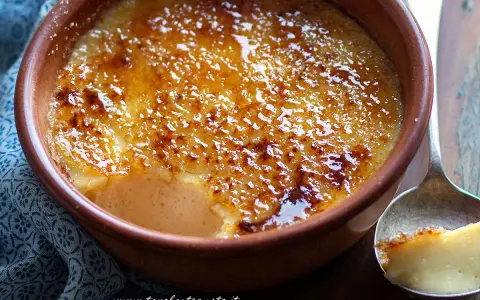 Un delizioso krem kataloński con crosta caramellata dorata, servito in una ciotola di terracotta.
