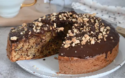 Torta soffice con amaretti e cioccolato fondente, glassata al cioccolato e cosparsa di briciole croccanti.