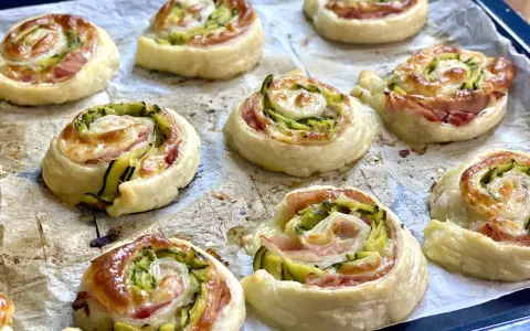 Rotolini dorati di pasta sfoglia con zucchine e scamorza filante, appena sfornati e pronti per essere gustati.