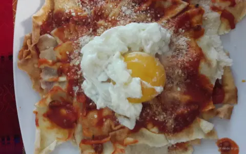 Spianata sarda come farcirla: croccante base con sugo rosso, formaggio grattugiato e un uovo in camicia.