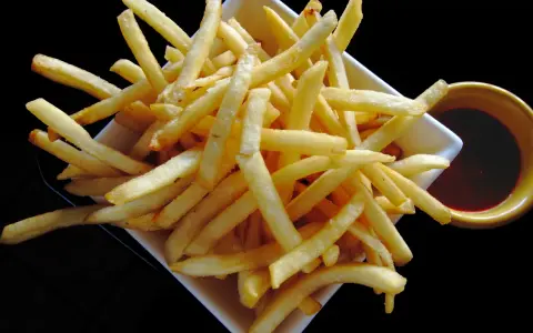 Un piatto di croccanti patatine fritte, perfette per un aperitivo, con una ciotolina di salsa rossa. Un classico intramontabile, come i veri frytki po włosku.