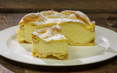 Fetta di Karpatka, dolce polacco con crema pasticcera e pasta choux, spolverata di zucchero a velo. Un delizioso karpatka przepis.