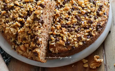 Torta noci e amaretti, soffice e golosa, ricoperta di noci tritate e gocce di cioccolato.
