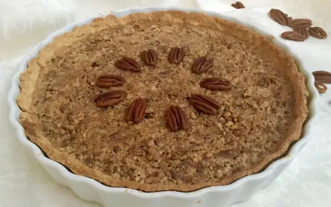 Torta di noci croccante e dorata, decorata con noci intere disposte a cerchio. Un delizioso pandi noci pronto da gustare.
