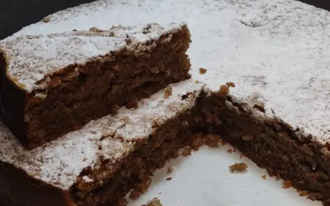 Una fetta di torta di noci della nonna, soffice e cosparsa di zucchero a velo, invita a un assaggio di tradizione.