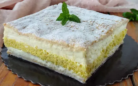 Una deliziosa torta di compleanno con pasta sfoglia e pan di spagna, farcita con crema e decorata con zucchero a velo e menta.