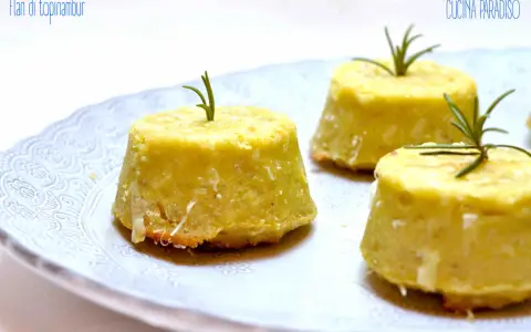 Flan di topinambur senza patate, dorati e profumati, guarniti con rosmarino fresco su un piatto bianco decorato.