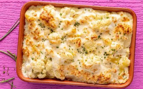 Sformato di cavolfiore e ricotta dorato e filante, guarnito con erba cipollina, pronto per essere gustato.