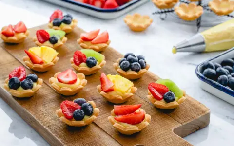 Deliziosi cestini di frutta ricetta, preparati con fragole, mirtilli, kiwi e ananas su una base di crema.