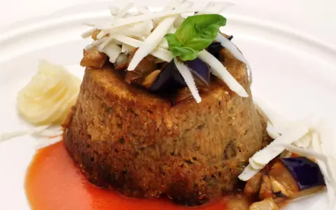 Sformato di melanzane leggero, guarnito con scaglie di formaggio, basilico e servito con salsa rossa e purè.