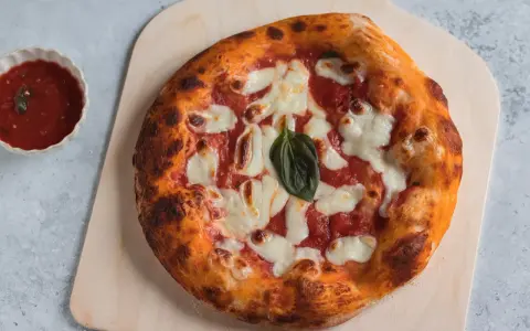 Pizza napoletana appena sfornata, con pomodoro, mozzarella filante e basilico fresco, pronta per essere gustata.