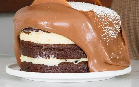 Torta al cioccolato a strati con glassa al cioccolato fusa che cola, decorata con perline bianche. Un vero tsunami di dolcezza!