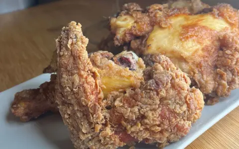 Pollo fritto croccante, un chrusty przepis che fa venire l'acquolina in bocca. Pezzi dorati e succulenti su un piatto bianco.