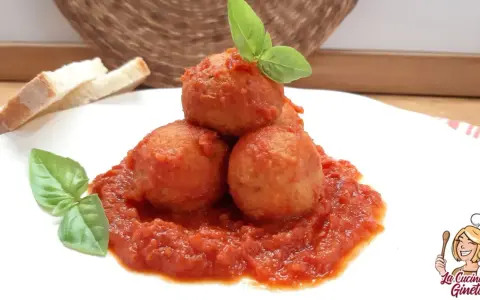 Polpette di pane in umido, un piatto confortante con pomodoro e basilico, accompagnato da fette di pane.
