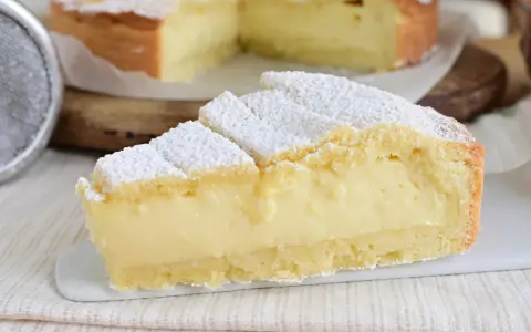 Fetta di crostata con abbondante crema allo yogurt, cosparsa di zucchero a velo.