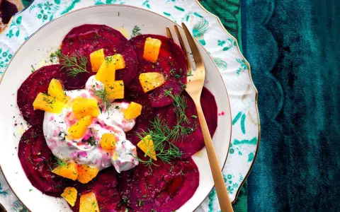 Delizioso carpaccio di barbabietola con crema, arancia e aneto su un piatto decorato.