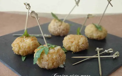 Deliziose polpette finger food con salsa, servite su una pietra scura, pronte per essere gustate.