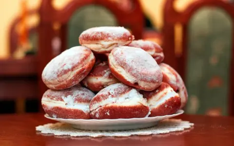 Pila di bomboloni zuccherati, pronti per il tłusty czwartek. Deliziosi dolcetti che invitano a festeggiare.