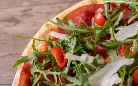 Pizza bresaola rucola e grana: un tripudio di sapori con bresaola, pomodorini, rucola fresca e scaglie di grana.